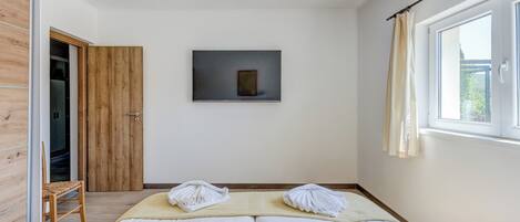A bedroom with a bed, a wooden wardrobe, a framed picture on the wall, and a window with curtains.
