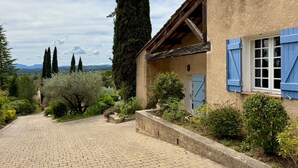 Un edificio rústico con fachada de piedra, un porche de madera y una ventana con contraventanas azules.