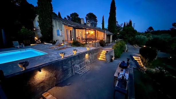 Un área junto a la piscina con pared de piedra, asientos exteriores y un patio bien iluminado.