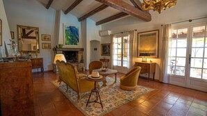 Una habitación tradicional con chimenea, muebles de madera y ventanas amplias.
