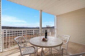 Un balcon avec une table et des chaises, une bouteille et un verre.