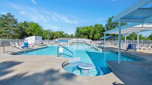 A swimming pool with a sun deck, lounge chairs, and a covered seating area.