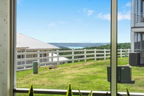 A view of a building with a white fence and grassy area in front. - Freshly Updated Condo with Table Rock Lake Access, Outdoor Pool, Mini Golf & Free Daily Tickets (Kimberling City)