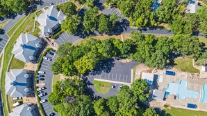 An aerial view of a residential area with multiple houses, a swimming pool, and a parking lot.