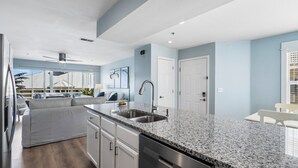 A modern kitchen with granite countertops, stainless steel appliances, and a large window overlooking a pool area.