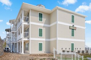 A multi-story building with a balcony on the second floor, a sign indicating it is a vacation rental, and a gated entrance.