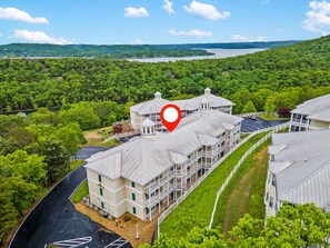Un hotel con un edificio central rodeado de exuberante vegetación y un lago al fondo.