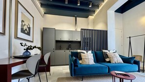 Un salon moderne avec un canapé bleu, une table à manger et des chaises. On y trouve également un coin cuisine avec des placards et un plan de travail.