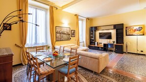 A living room with a glass dining table, a sofa, a TV, and a coffee table. - Graceful Home Genova City Center, Genova, Italy (Genova)