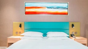 A hotel room with a large bed, two bedside tables, a nightstand with a phone, and a painting on the wall. - Wode  Hotel Tengzhouhuochezhandian (Zaozhuang)