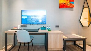 A modern room with a desk, chair, and a flat-screen TV mounted on the wall. - Wode  Hotel Tengzhouhuochezhandian (Zaozhuang)
