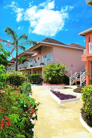 A hotel with a central courtyard, balconies, and a clear sky. - Shields Negril Villas (Negril)