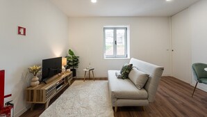 Un salon moderne avec un canapé, un téléviseur et une petite table d’appoint.