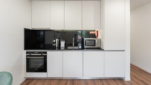 Une cuisine moderne avec des meubles blancs, un plan de travail noir, un four à micro-ondes, un grille-pain et un four encastré.