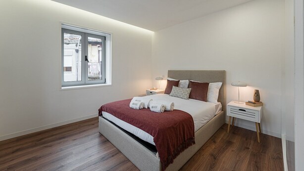 Une chambre moderne avec un grand lit, des tables de chevet, une fenêtre et une vue sur l’extérieur.