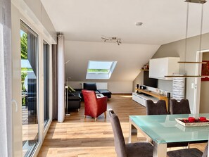 A modern interior with a dining area, a sofa, and a TV. - Siebenstern**** Vacation Rental - 4-star vacation rental with high-speed Wi-Fi, balcony & (Winterberg)