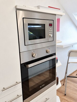A kitchen with a built-in microwave, oven, and a small countertop. - Siebenstern**** Vacation Rental - 4-star vacation rental with high-speed Wi-Fi, balcony & (Winterberg)