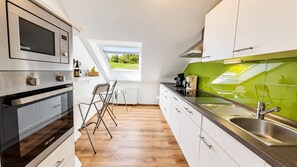 A modern kitchen with a built-in microwave, a large window, and a view of the outdoors. - Siebenstern**** Vacation Rental - 4-star vacation rental with high-speed Wi-Fi, balcony & (Winterberg)