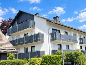 A multi-story residential building with balconies, a tiled roof, and a clear sky. - Siebenstern**** Vacation Rental - 4-star vacation rental with high-speed Wi-Fi, balcony & (Winterberg)