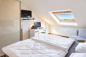 A bedroom with a bed, a desk with a computer, a TV, and a skylight. - Siebenstern**** Vacation Rental - 4-star vacation rental with high-speed Wi-Fi, balcony & (Winterberg)