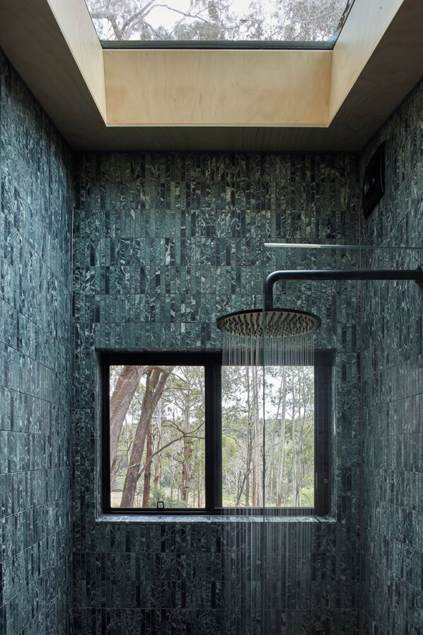 A bathroom with a skylight, a shower, and a window with a view of trees. - A bespoke, luxe, off-grid cabin beside Monga National Park. Mins to Braidwood (Reidsdale)