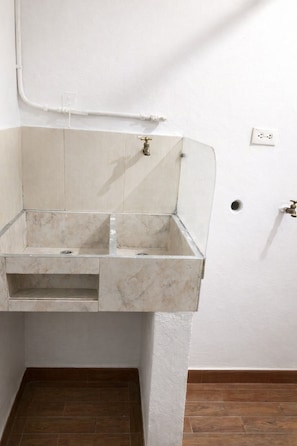 A bathroom with a marble sink, a white wall, and a wooden floor.