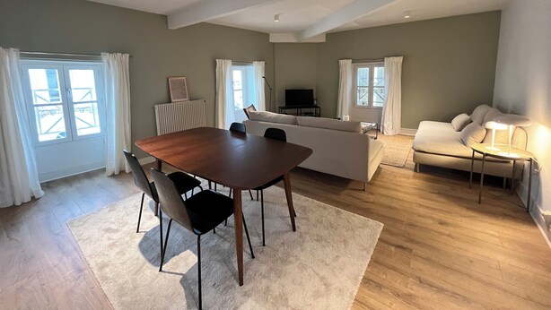 A spacious living area with a dining table, sofa, and a TV.