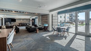 A spacious indoor area with a bar, seating, and large windows offering views of buildings and mountains. - Convention Ctr! Spacious 2BR/2BA-Spa,Pool,Gym,Pkg (Salt Lake City)