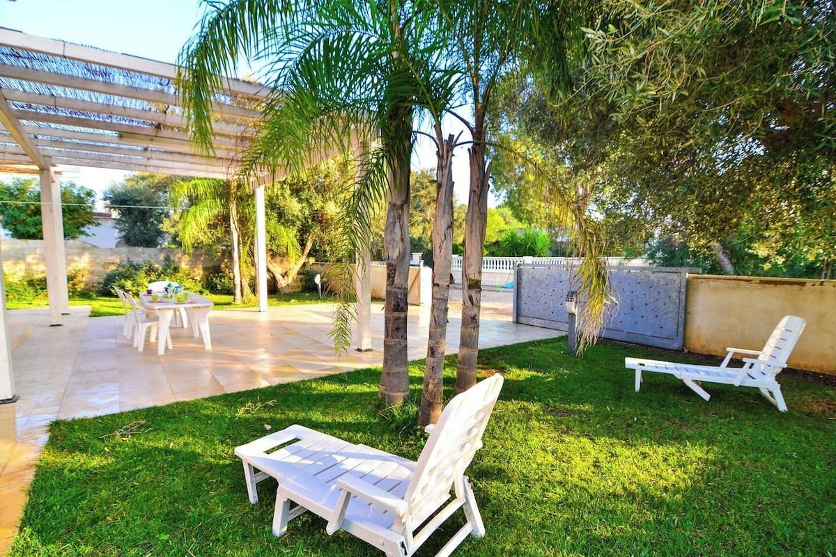 Une terrasse extérieure dotée d’un espace salon couvert, d’une table avec des chaises et de deux fauteuils de relaxation.