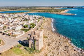A coastal town with a prominent stone building, narrow streets, and a clear view of the sea. - Boomerang Village (Manduria)