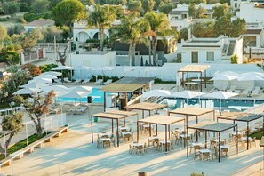 A resort with outdoor seating, a pool, and a view of the surrounding buildings. - Boomerang Village (Manduria)