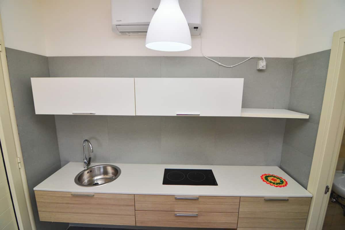 Une cuisine moderne dotée d’un évier en acier inoxydable, d’une plaque de cuisson à induction noire et d’un plan de travail blanc.