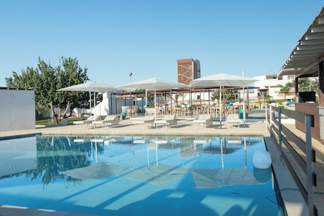 Una piscina al aire libre de temporada, sombrillas