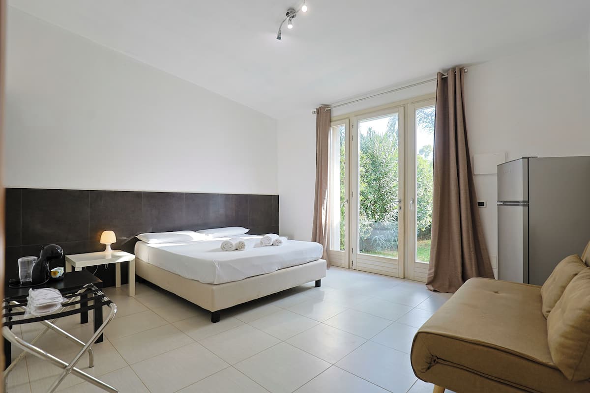 Une chambre d’hôtel moderne équipée d’un lit, d’un canapé, d’un bureau avec une lampe et d’un réfrigérateur.