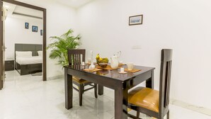 A dining area with a wooden table, chairs, and a potted plant. - Quartz -Parfait Street Near Fortis (Gurugram)