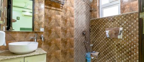 A bathroom with a marble wall, a sink, a mirror, and a shower area.