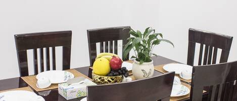 A dining table with chairs, a fruit bowl, and a potted plant.