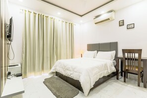 A bedroom with a bed, a chair, a desk, an air conditioner, and a curtain. - Quartz -Parfait Street Near Fortis (Gurugram)