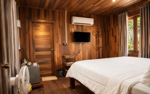 A wooden-paneled room with a bed, an air conditioning unit, a television, and a window with curtains. - Punnattha House by Peema Villa (U Thong)
