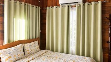 Een kamer met een bed, gordijnen, een airconditioning en houten wanden.