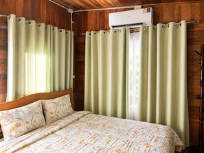 A room with a bed, curtains, an air conditioning unit, and wooden walls. - Punnattha House by Peema Villa (U Thong)