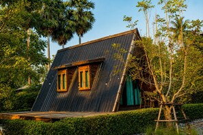 A house with a sloped roof, two windows with wooden frames, and a wooden deck. - Punnattha House by Peema Villa (U Thong)