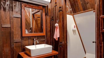A bathroom with a wooden vanity, a white sink, a mirror, and a towel hanging on the wall.
