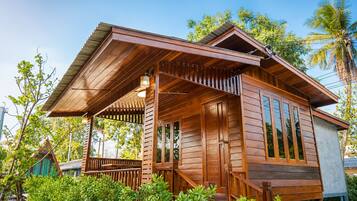 A wooden cabin with a porch, large windows, and a sloped roof.
