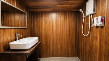 Ein Badezimmer mit Holzvertäfelung, einem weißen Waschbecken, einem Spiegel und einer Duschkabine.