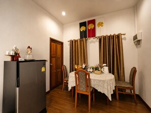 A dining area with a table set for two, a refrigerator, and a door. - Punnattha House by Peema Villa (U Thong)
