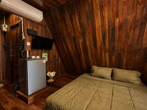 A bedroom with a bed, a television mounted on the wall, and a refrigerator. - Punnattha House by Peema Villa (U Thong)
