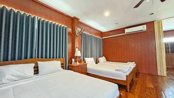 A hotel room with two beds, a ceiling fan, an air conditioning unit, and a window with curtains.
