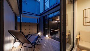 Un intérieur moderne avec un plancher en bois, un coin salon comprenant un banc et un fauteuil, et une porte vitrée donnant sur un balcon.