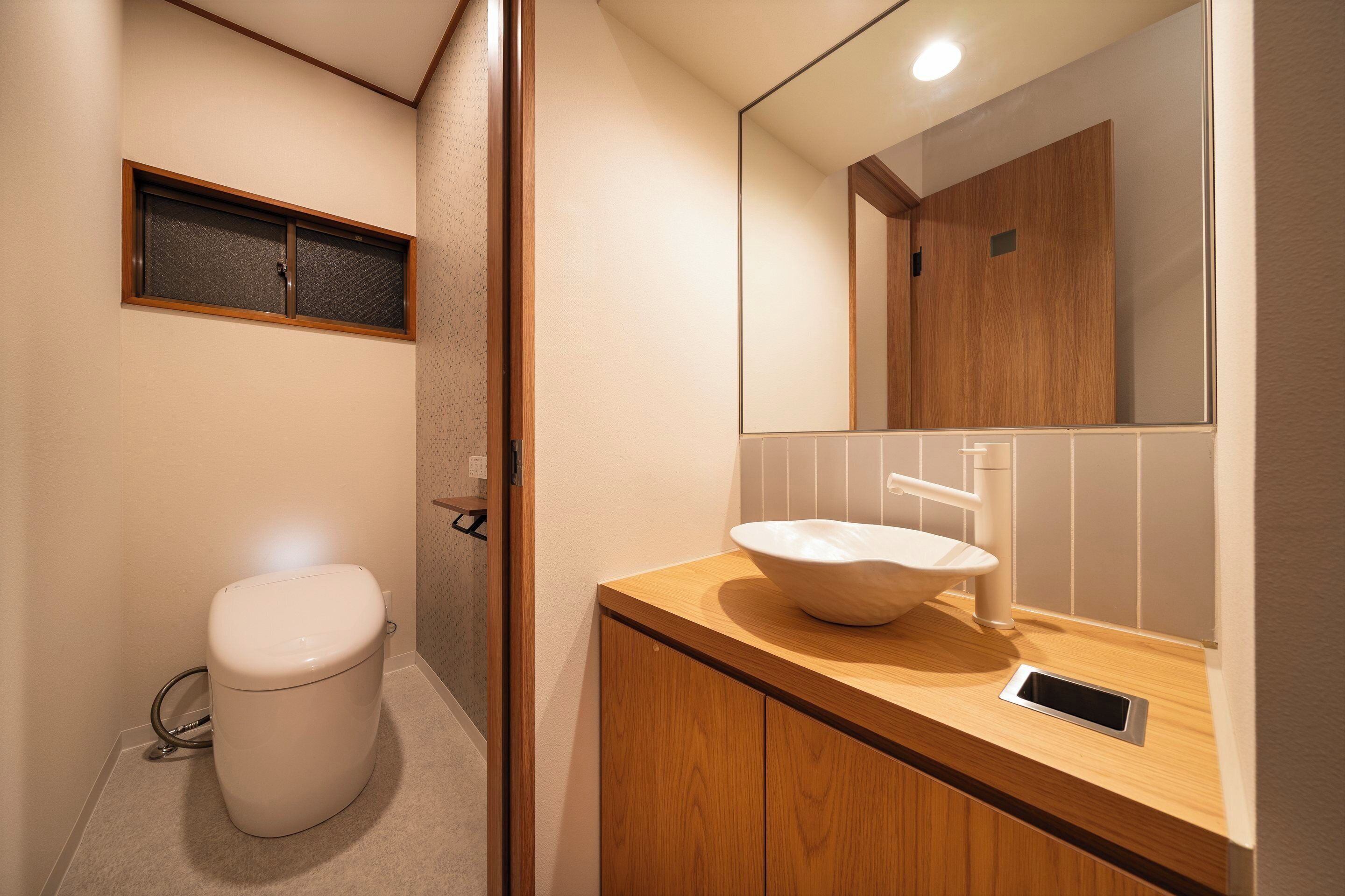 A modern bathroom with a toilet, a sink, and a mirror.